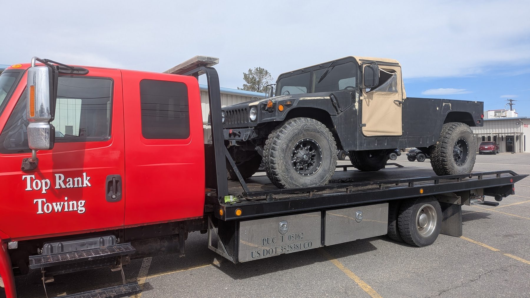 Flatbed towing a military Humvee